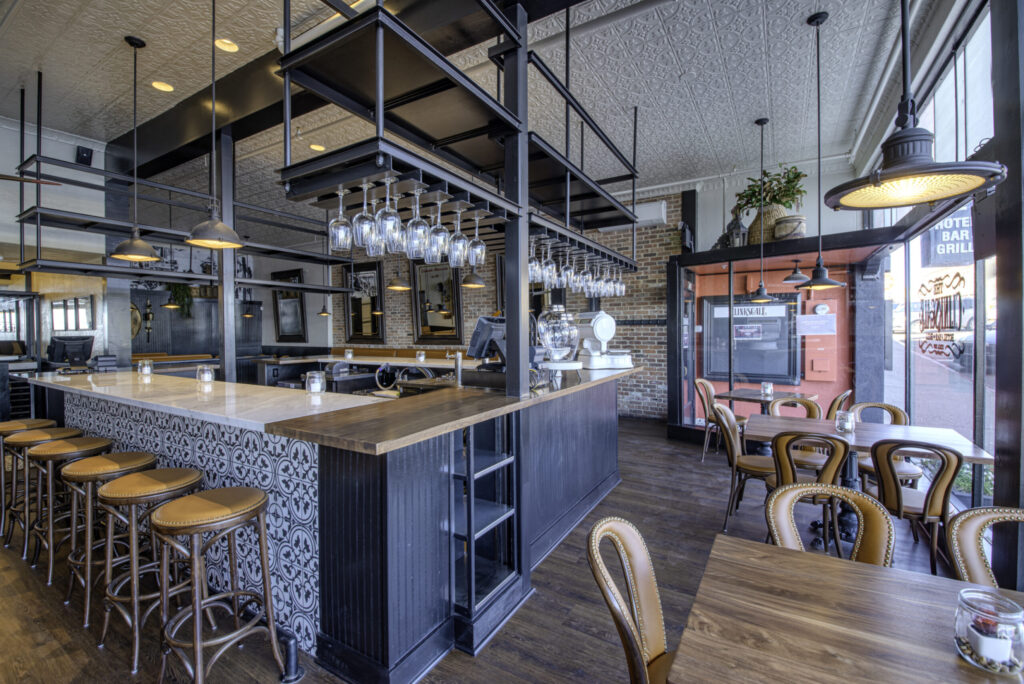Bar and dining room looking toward the street entrance, with exposed brick and overhead steel shelving