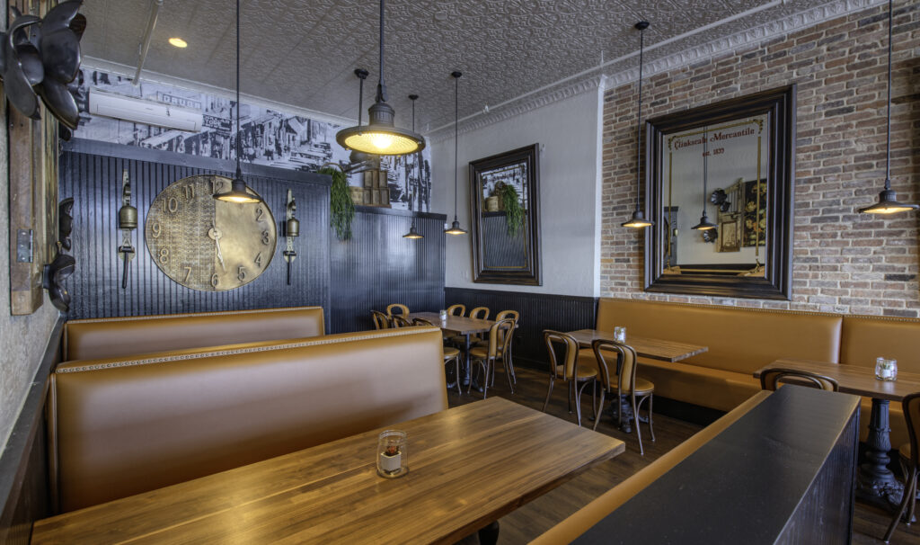 Dining area with leather banquettes, exposed brick, an antique wall clock and black and white photo murals