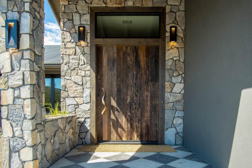 Front door in reclaimed timber, set between rough stone piers