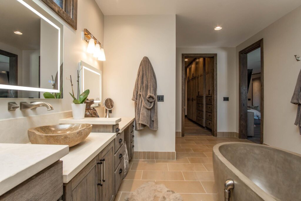 Bathroom with twin stone basins along the vanity and the tub beyond