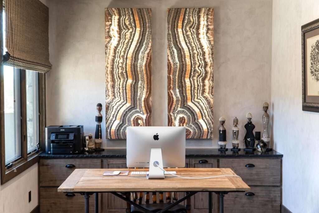 Study with a desk under the window and framed pieces above the credenza