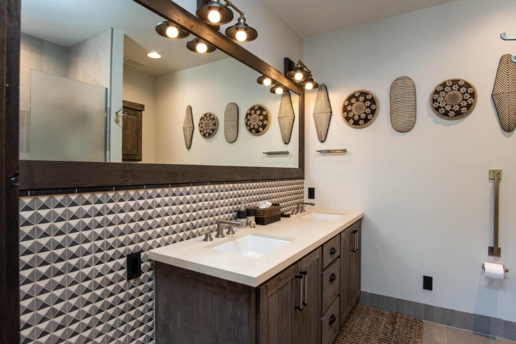Double vanity below a long mirror, with woven shields and baskets along the wall