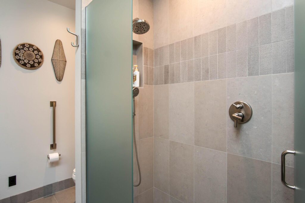 Tiled shower with a glass screen beside woven wall pieces