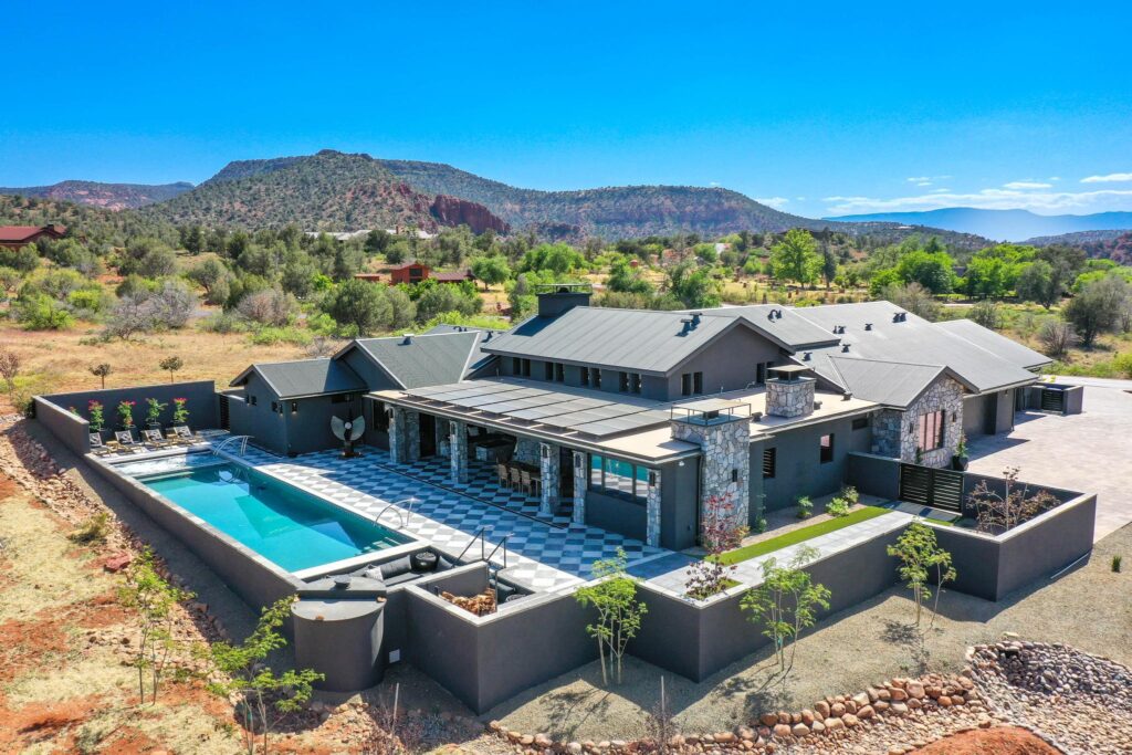Aerial view of a modern custom home and pool built by Kirkwood Builders near Sedona, Arizona, with red rock country behind it