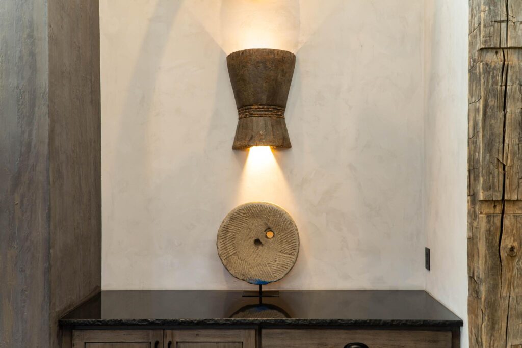 Carved drum mounted as a wall light above a low stone shelf