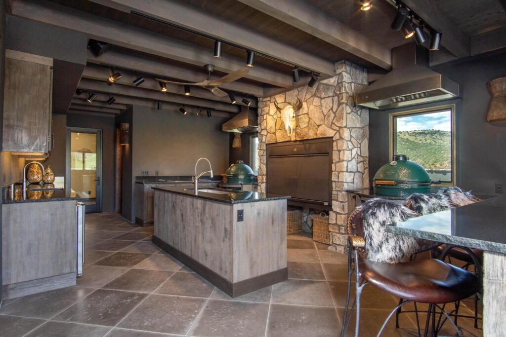 Outdoor kitchen with two islands, a stone chimney breast and grills set into the counter