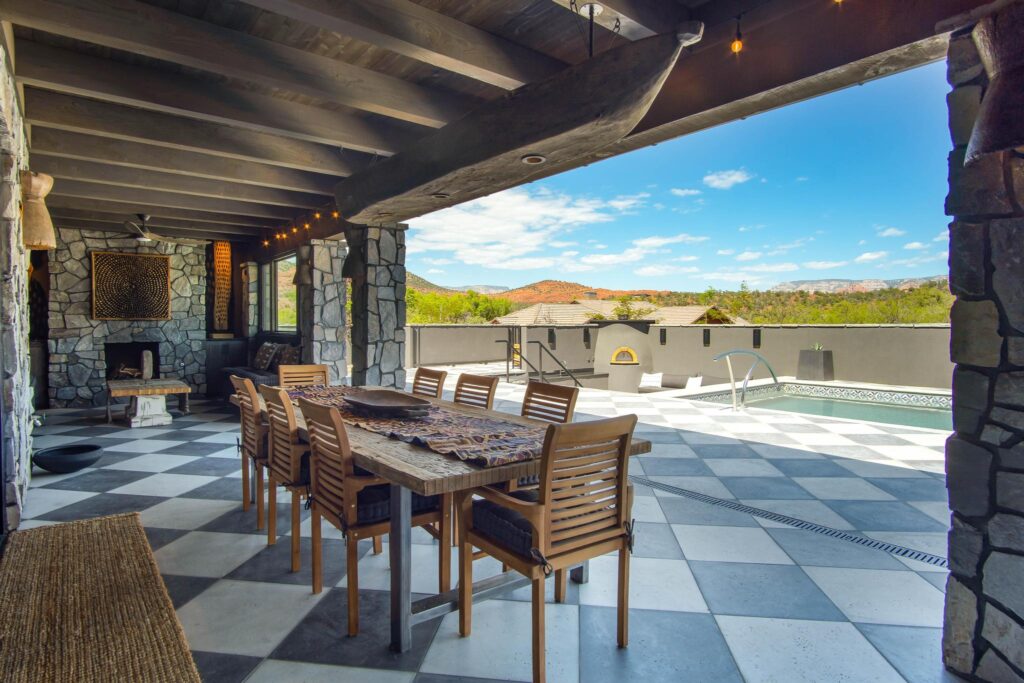 Covered pavilion with the dining table set on the checkerboard stone floor, pool beyond