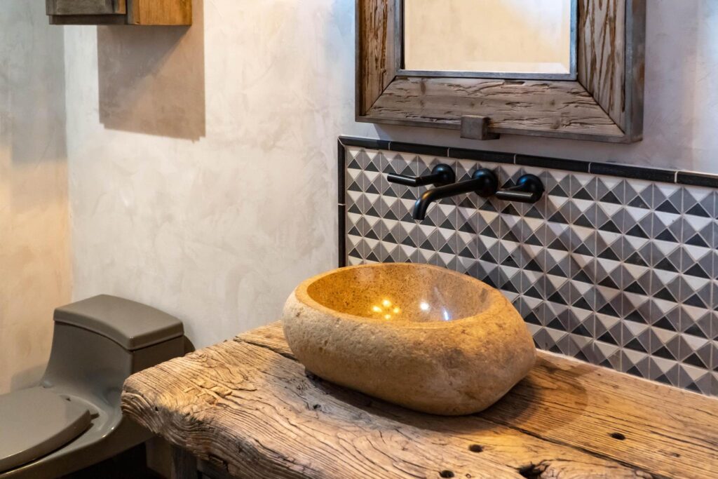 Stone basin on a reclaimed timber counter against a textured tile wall