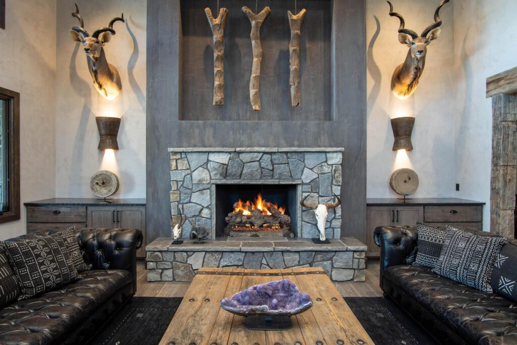 Living room around a stone fireplace with a lit fire and leather seating either side