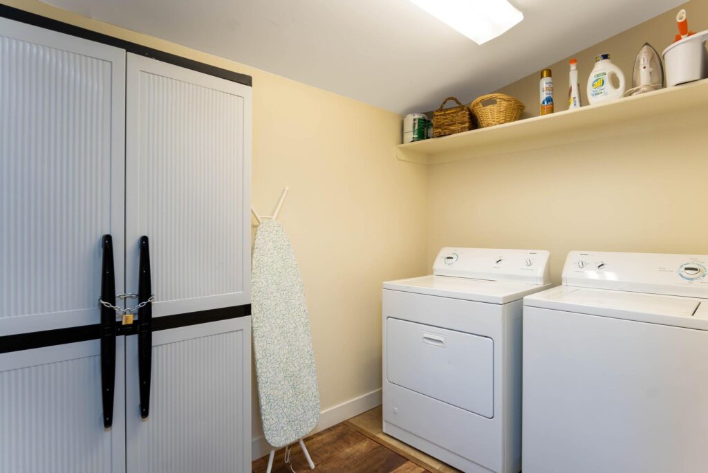 Laundry room with a side-by-side washer and dryer, louvered doors on black barn hardware and a skylight