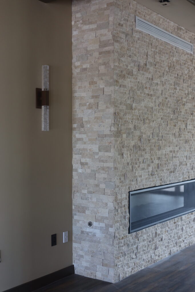 The stone fireplace wall and its sconce before finishes went in
