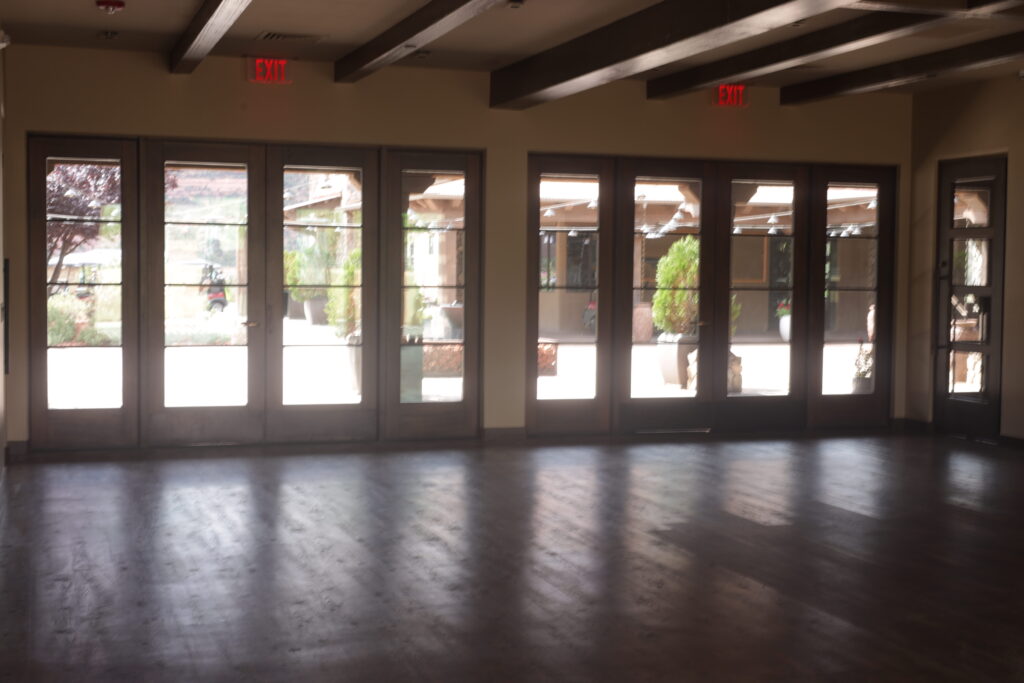 Clubhouse room before fit-out, with exposed timber beams and a wall of glass doors