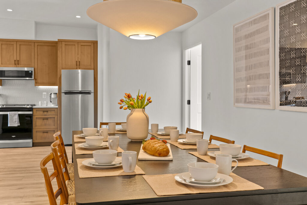View from the dining table toward the kitchen, with stainless appliances and light-toned cabinets