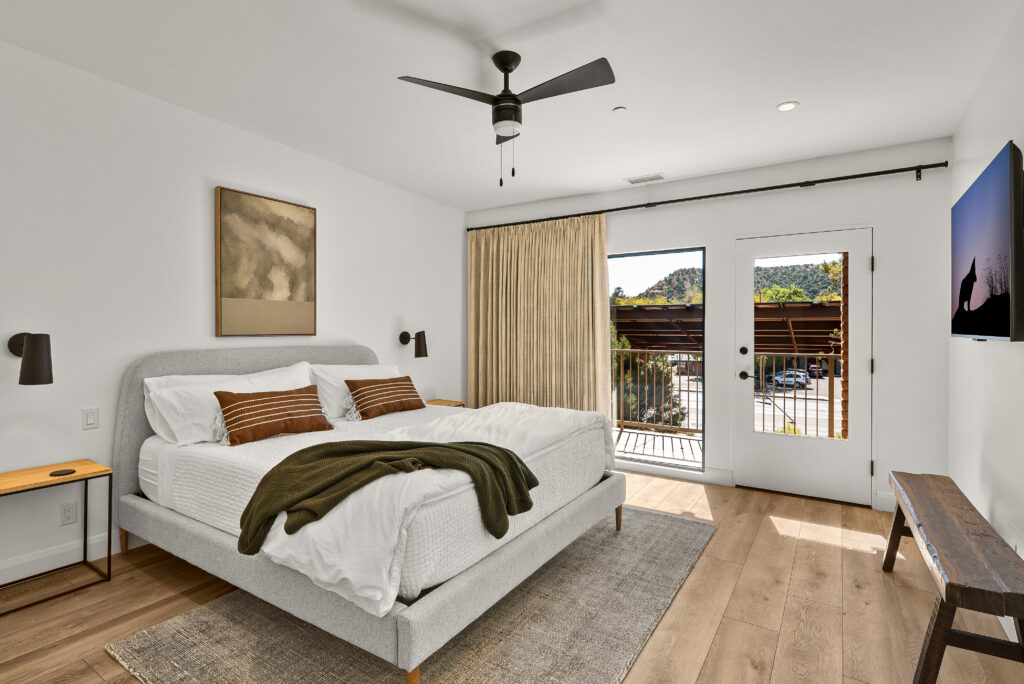 Bedroom with a king bed, ceiling fan, and a glass door opening to a private balcony
