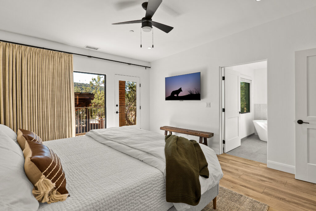King bedroom with a balcony door on one side and an open bathroom doorway on the other