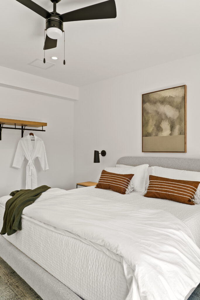 Bed with a robe hanging on a wall hook and framed art above the headboard