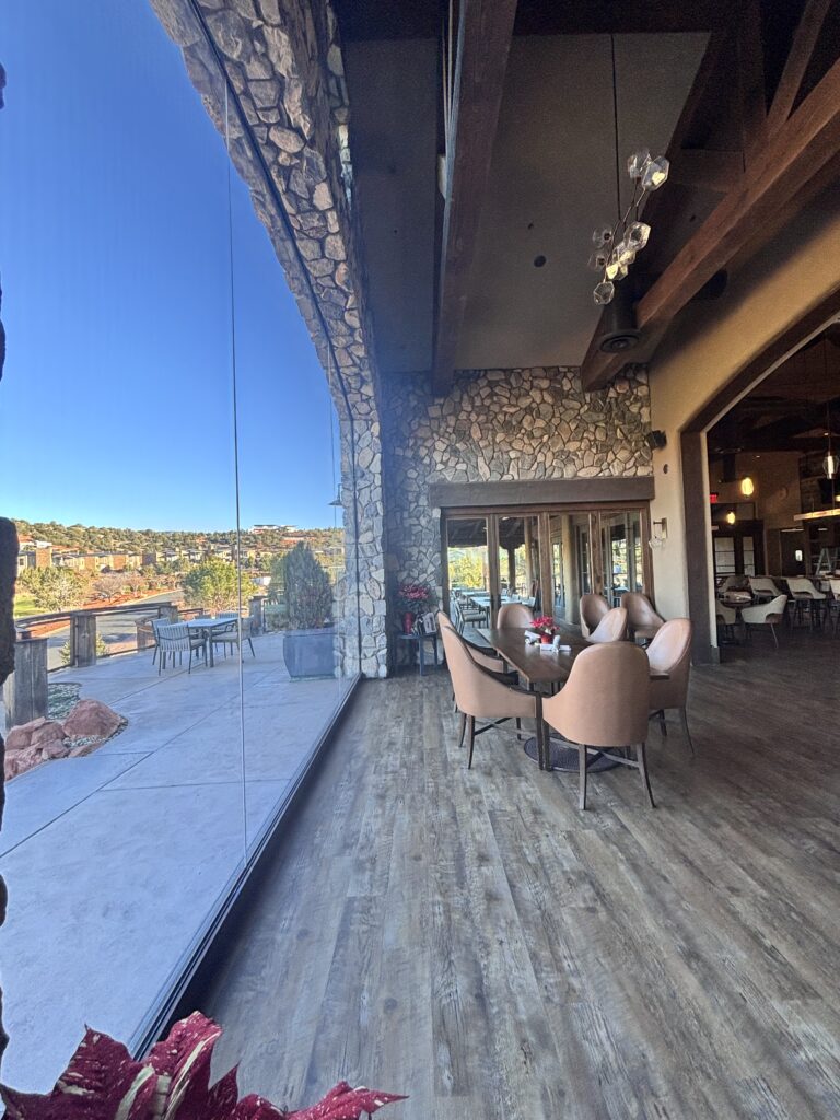 Dining room seating beside the full-height glass, with the terrace and red rock beyond