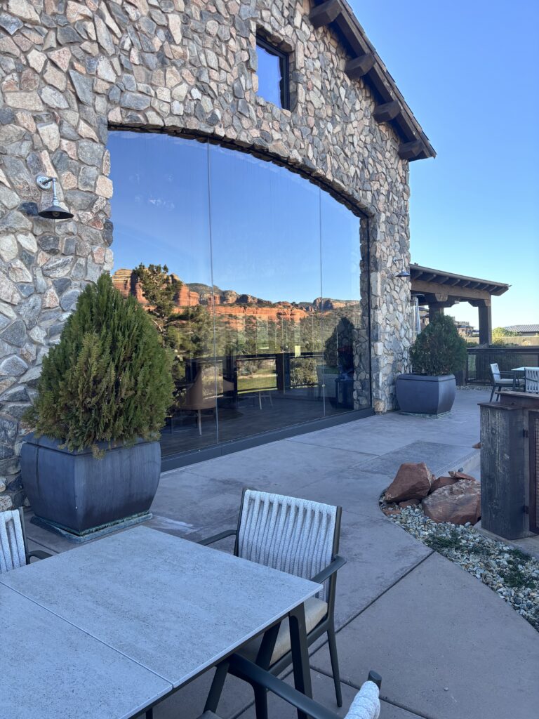 Glass wall set between stone columns, framing the red rock view from the terrace