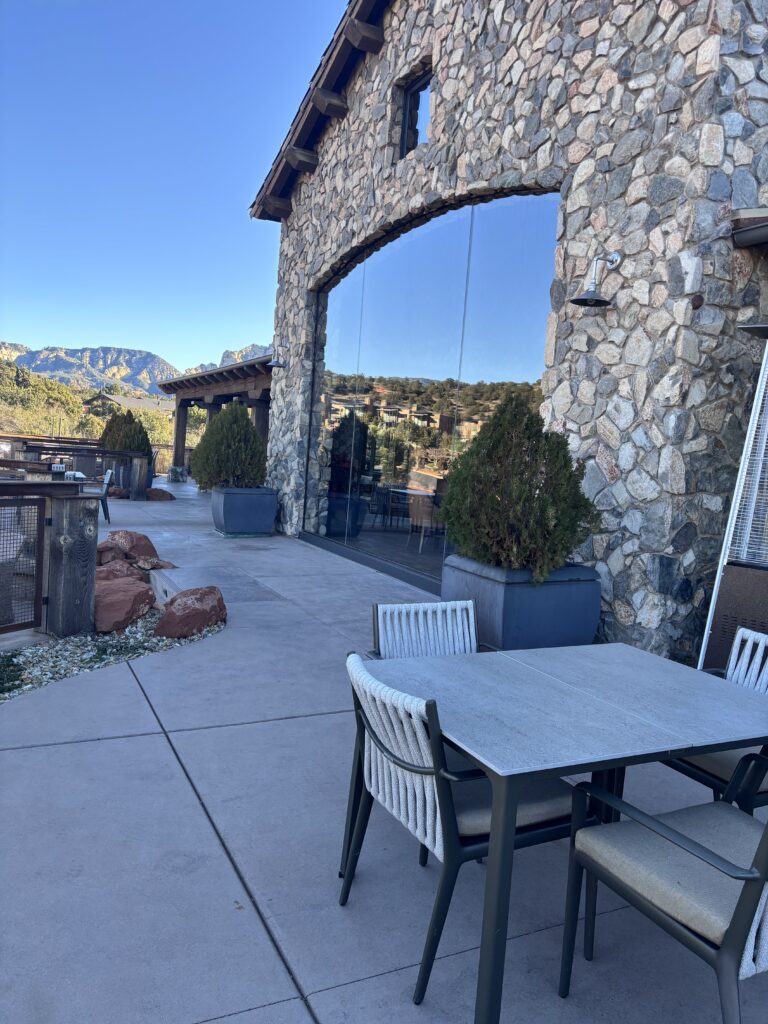 Terrace with stone columns and full-height glass, planters and red rock boulders