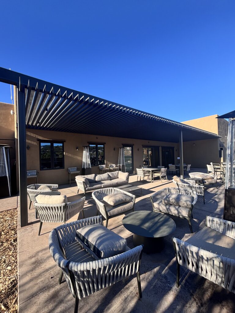 Lounge and dining seating on the covered terrace, looking along the louvered pergola