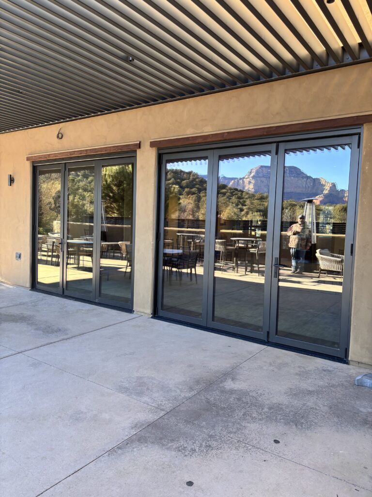 Sliding glass doors opening from the clubhouse onto the terrace, with red rock beyond