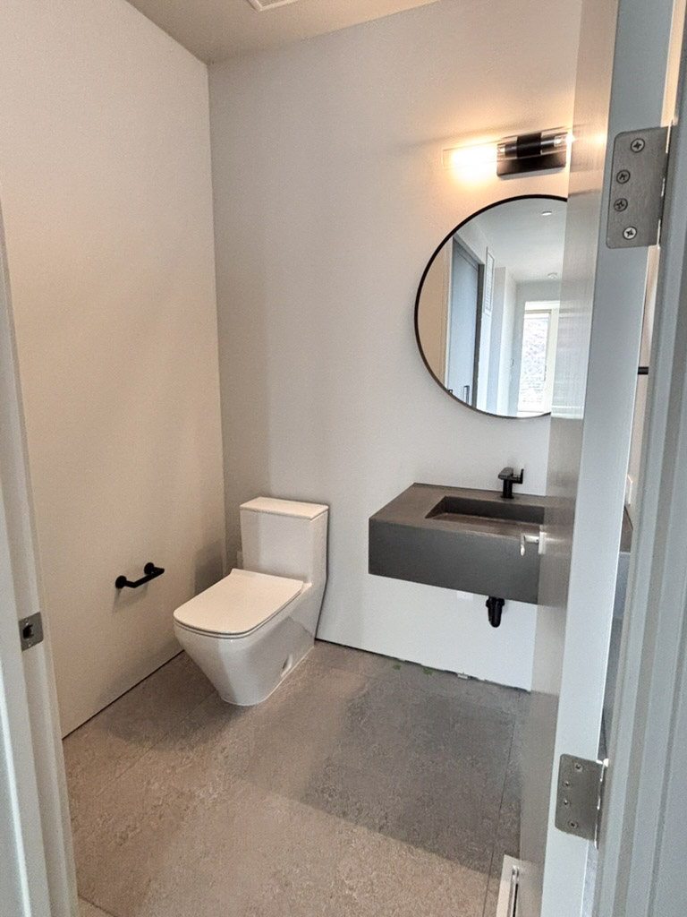 Powder room with a floating stone basin and a round mirror