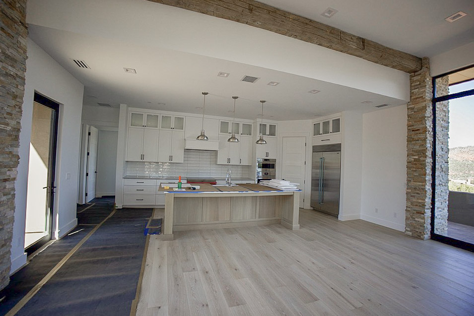 Kitchen with a long island, pendant lights and stacked stone at the corner