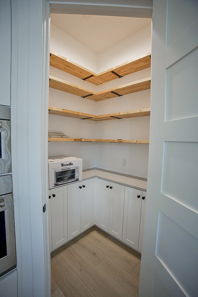 Pantry fitted with timber open shelving above white cabinets