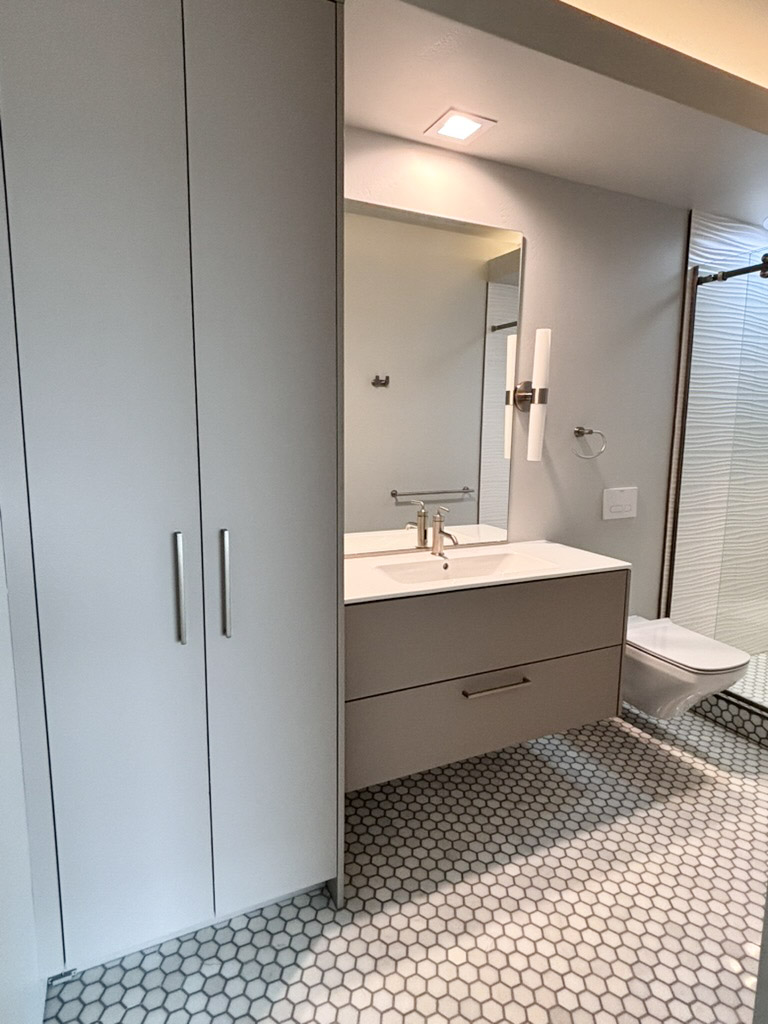 Bathroom with a floating vanity, tall storage and a lit mirror