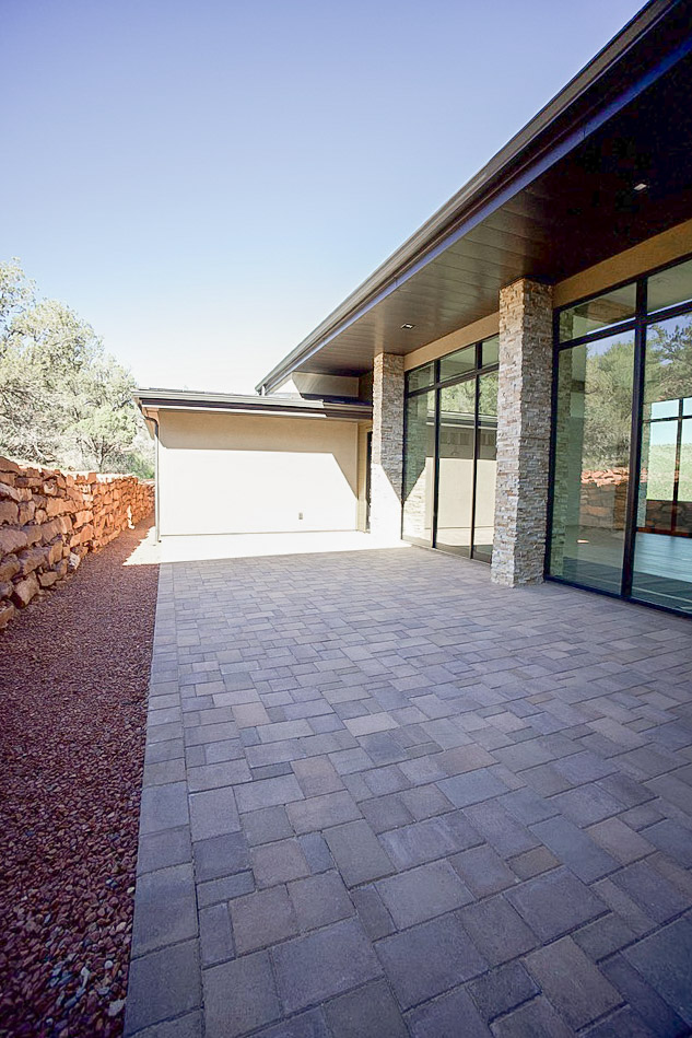 Paver courtyard between the house and a dry-stacked rock retaining wall