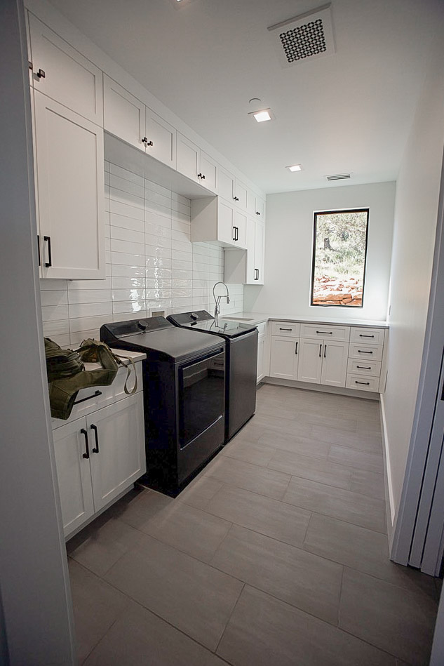 Laundry room with side-by-side machines, a sink and a window over the counter