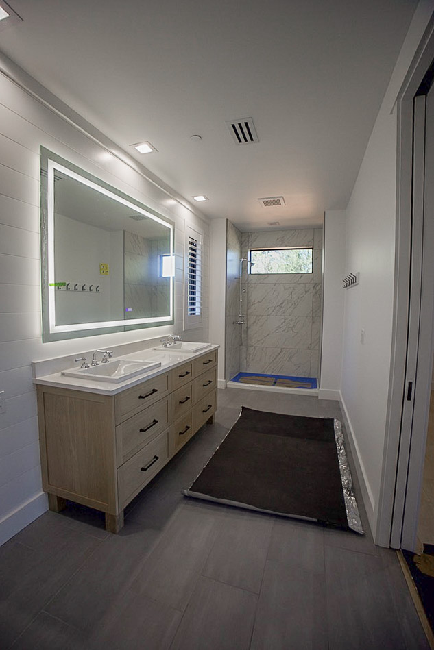 Primary bathroom with a double vanity, lit mirror and a tiled walk-in shower