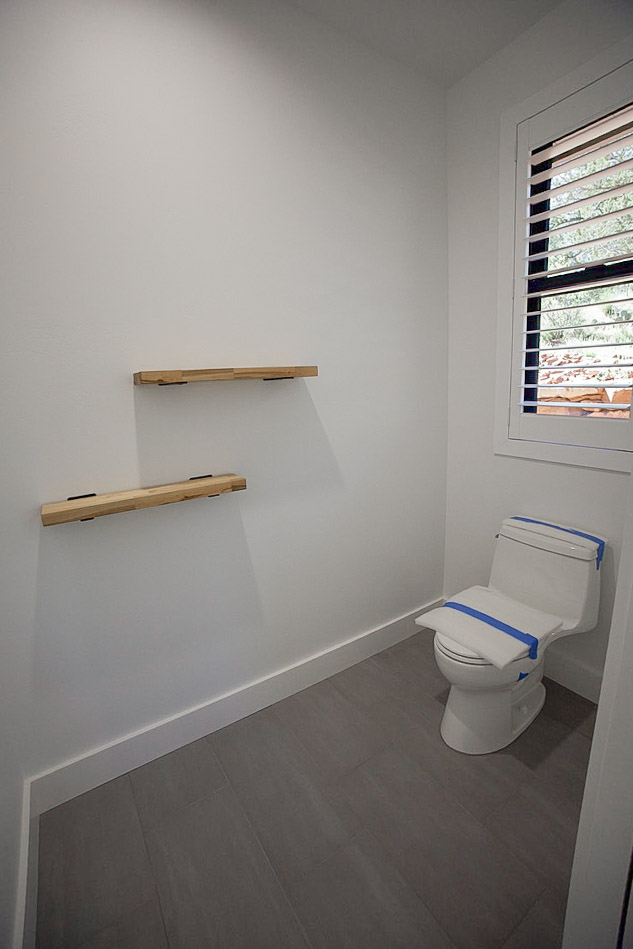 Bathroom with timber floating shelves and a window to the rocks outside