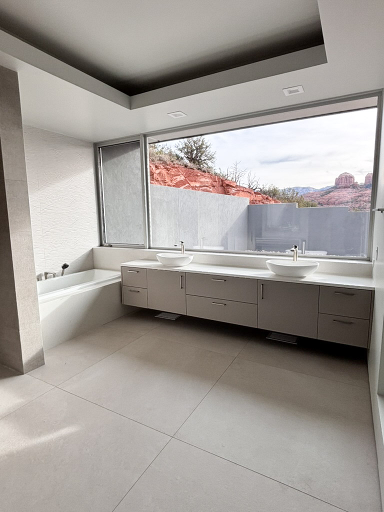 Primary bathroom with vessel basins along a window facing the red rock