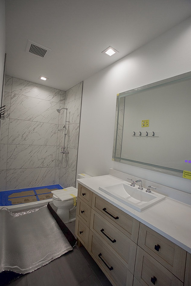 Bathroom with a tiled walk-in shower alongside the vanity and mirror