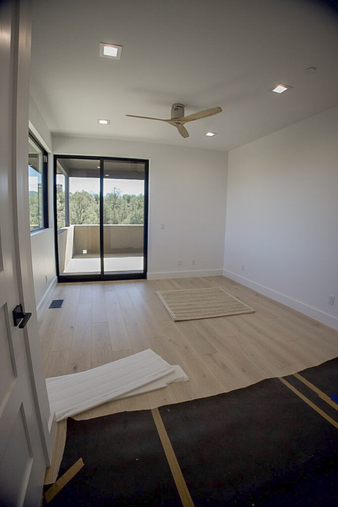 Bedroom with a sliding door onto the covered deck and trees beyond