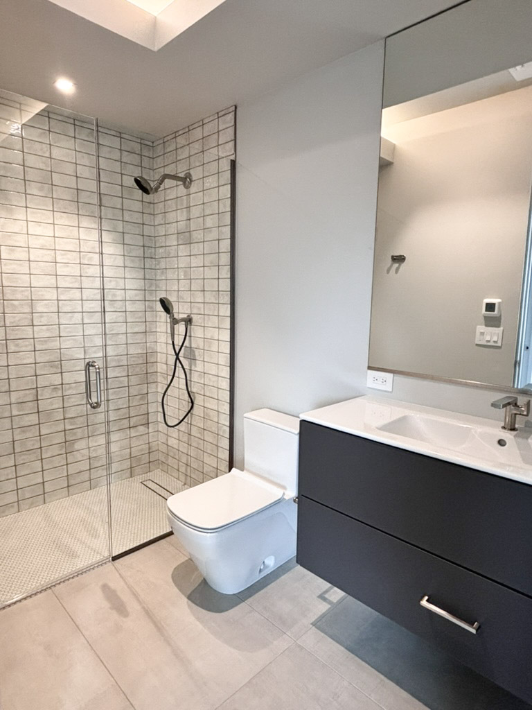Bathroom with a tiled walk-in shower alongside a floating vanity