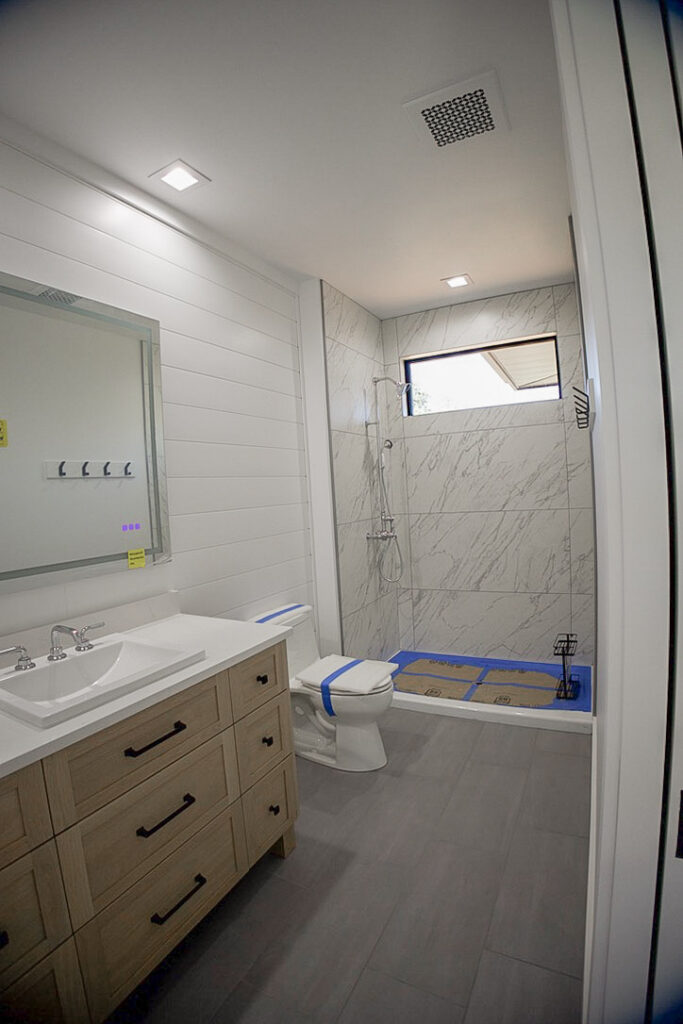 Guest bathroom with a shiplap wall, tiled shower and a high window