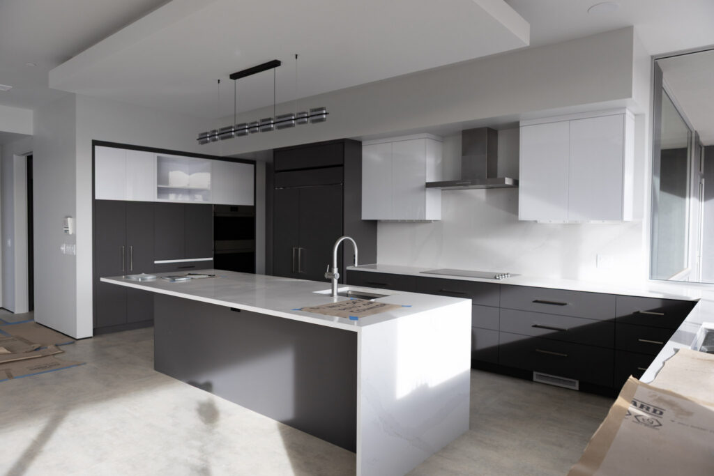 Kitchen with a waterfall-edge island, dark cabinetry and a wall of appliances