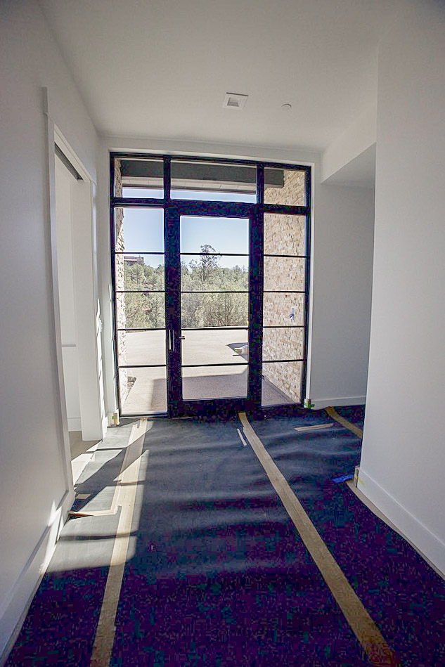 Entry hall looking out through black-framed glass doors to the patio and junipers