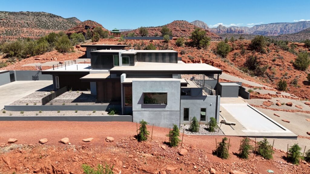 The house from the side, stepping down the slope in stucco and stone