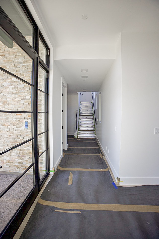 Hallway running past a stacked stone wall toward the stairs