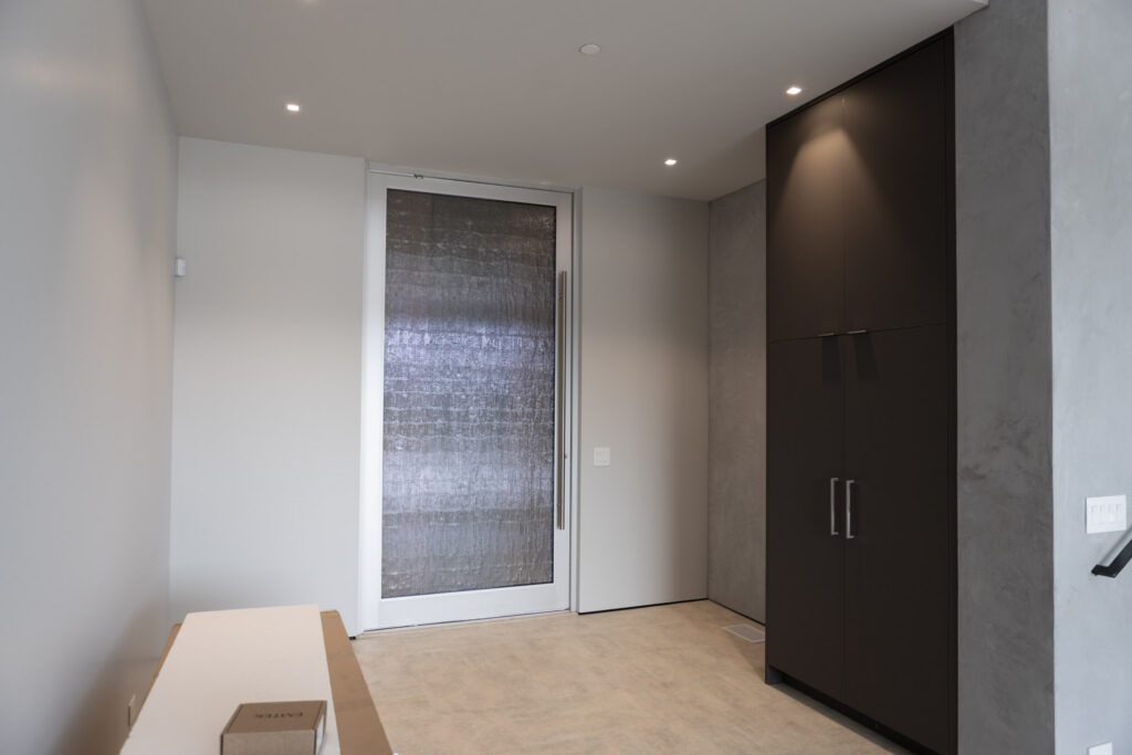 Entry with a backlit panel door beside full-height cabinetry