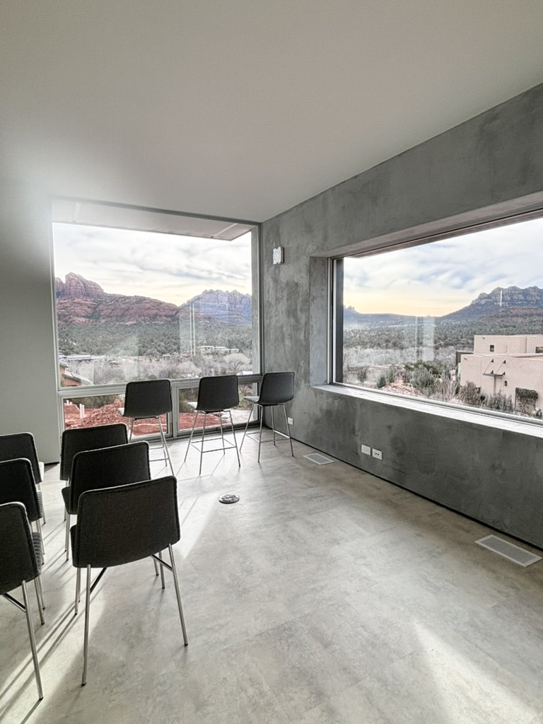 Corner of glass framing the red rock, with seating pulled up to the window
