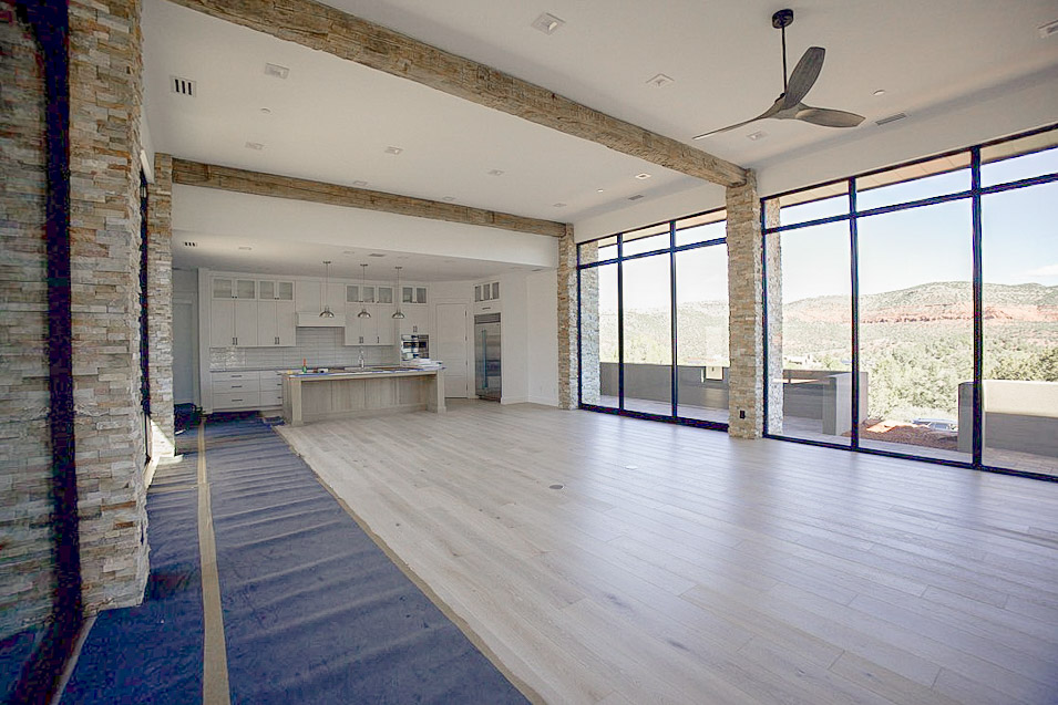 Great room looking toward the kitchen, stacked stone columns and timber beams overhead