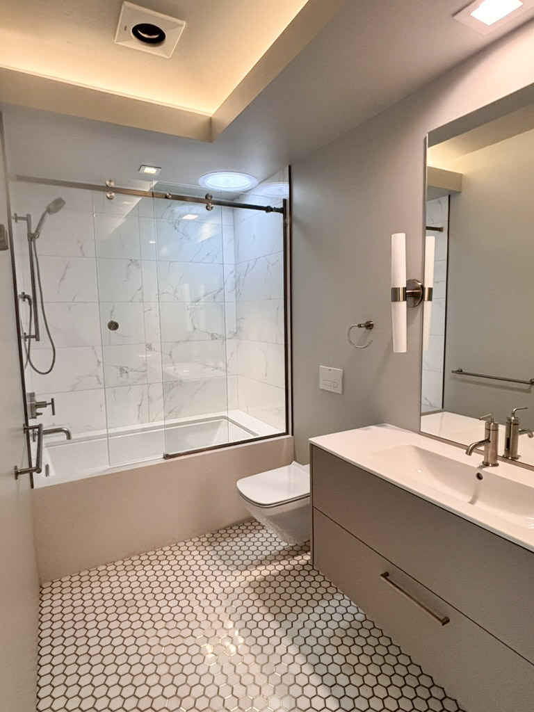 Bathroom with a tiled shower over the tub and a wall-hung vanity