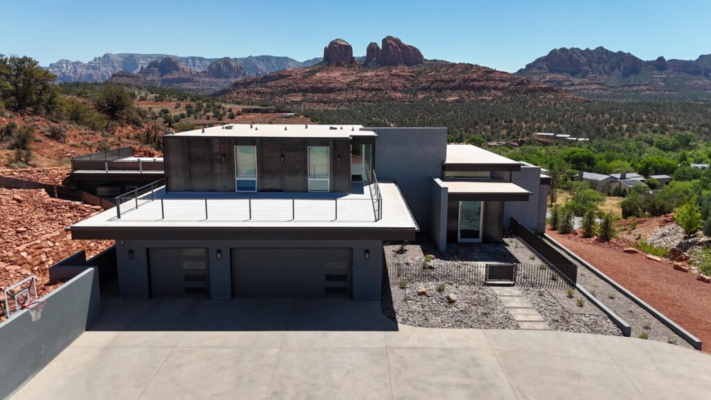 The approach elevation, where the house reads low with the upper floor set back